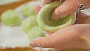 將均分的艾草面團搓成圓，挖一個窩，放入餡心，再搓成圓。